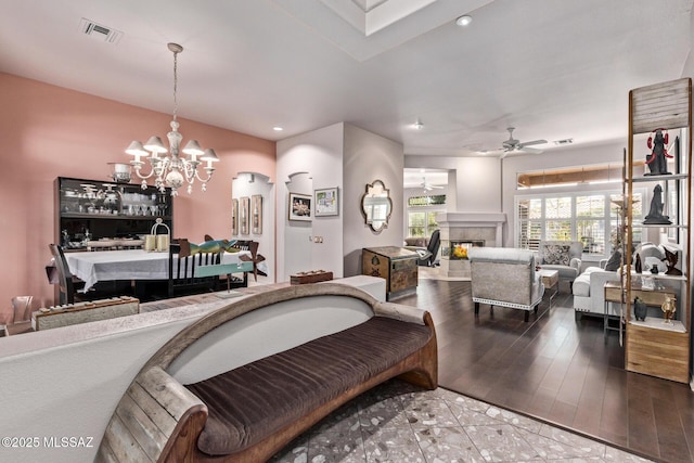 living room with ceiling fan with notable chandelier, a fireplace, and hardwood / wood-style flooring