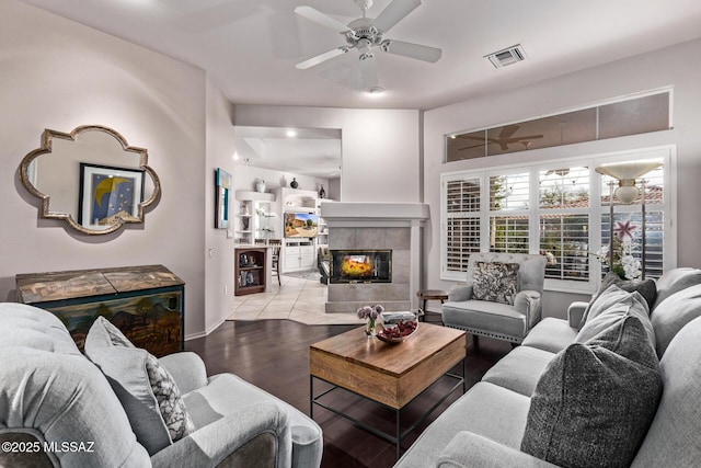 living room with ceiling fan, light hardwood / wood-style floors, and a tile fireplace