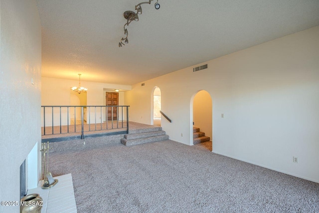 unfurnished room featuring a textured ceiling, carpet floors, and a chandelier