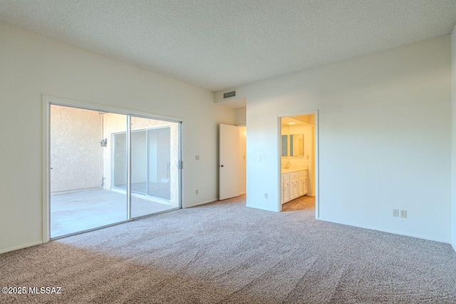 unfurnished bedroom with connected bathroom, light colored carpet, and a textured ceiling