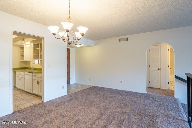 carpeted spare room with sink, a chandelier, and a textured ceiling