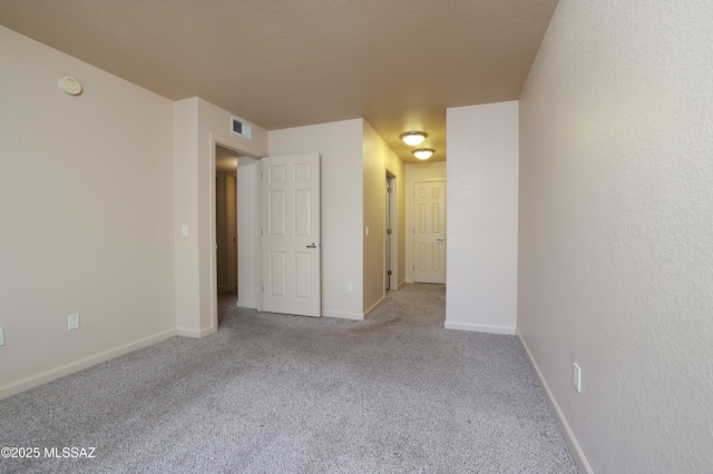 unfurnished room with light colored carpet and a textured ceiling
