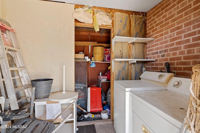 laundry room with brick wall and washer and clothes dryer