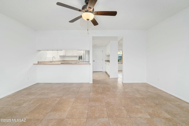 unfurnished living room with light tile patterned flooring, ceiling fan, and sink