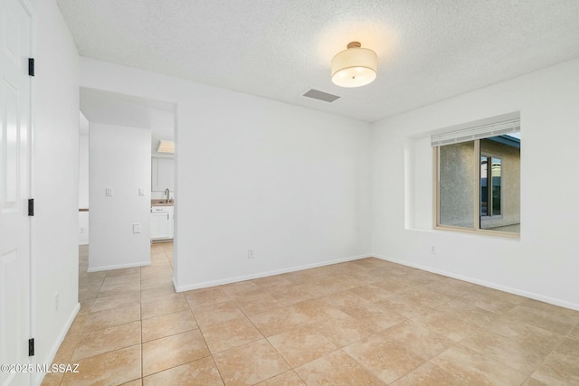 tiled empty room with sink and a textured ceiling