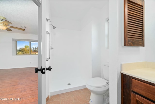 bathroom with toilet, a textured ceiling, vanity, ceiling fan, and tile patterned flooring