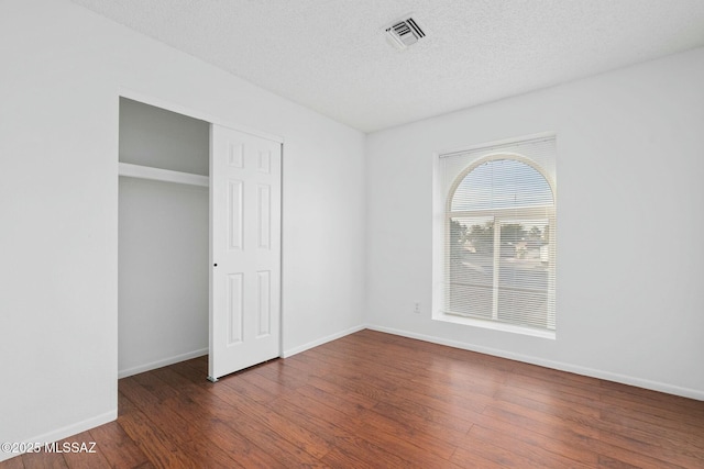 unfurnished bedroom with dark hardwood / wood-style flooring, a closet, and a textured ceiling