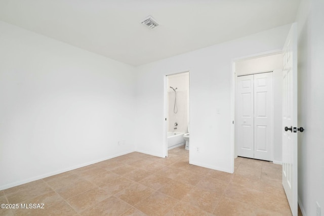 unfurnished bedroom with connected bathroom and a closet