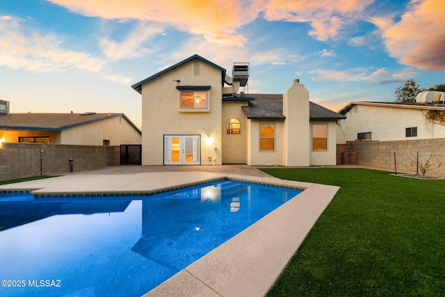 pool at dusk with a yard, a patio area, and french doors