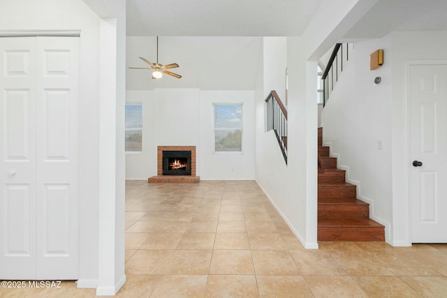 staircase featuring tile patterned flooring, a brick fireplace, and ceiling fan