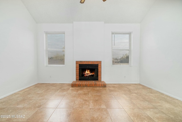 unfurnished living room with ceiling fan, a brick fireplace, and light tile patterned floors