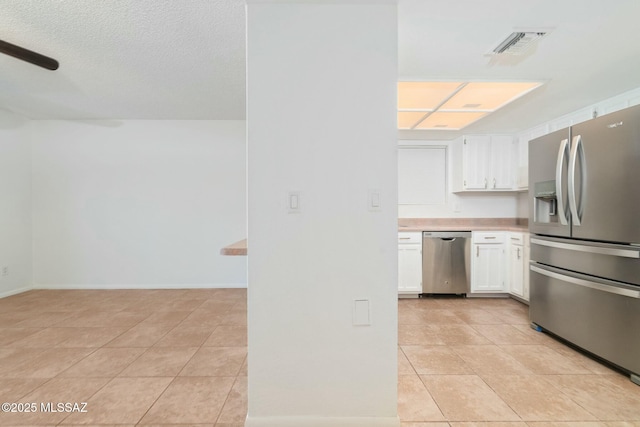 kitchen featuring appliances with stainless steel finishes, light tile patterned floors, and white cabinets