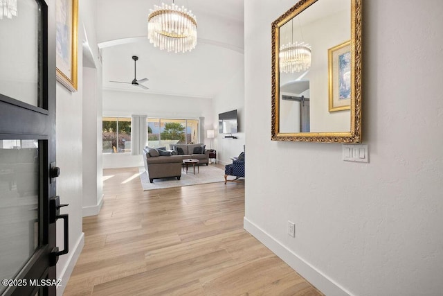 corridor featuring an inviting chandelier, lofted ceiling, and light wood-type flooring