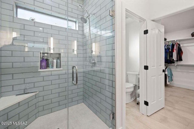 bathroom featuring a shower with shower door and toilet