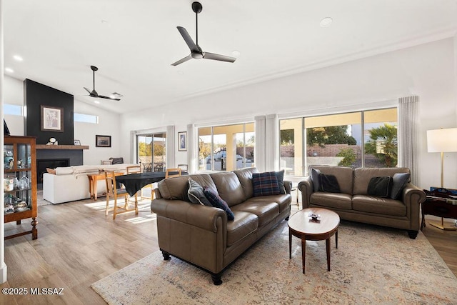 living room with ceiling fan, plenty of natural light, light hardwood / wood-style floors, and vaulted ceiling