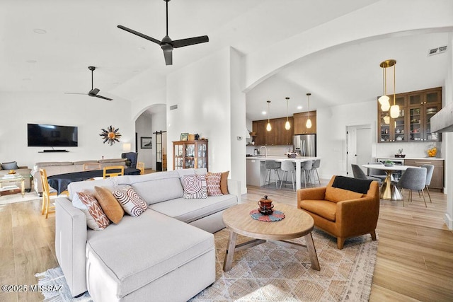 living room with vaulted ceiling, light wood-type flooring, and ceiling fan