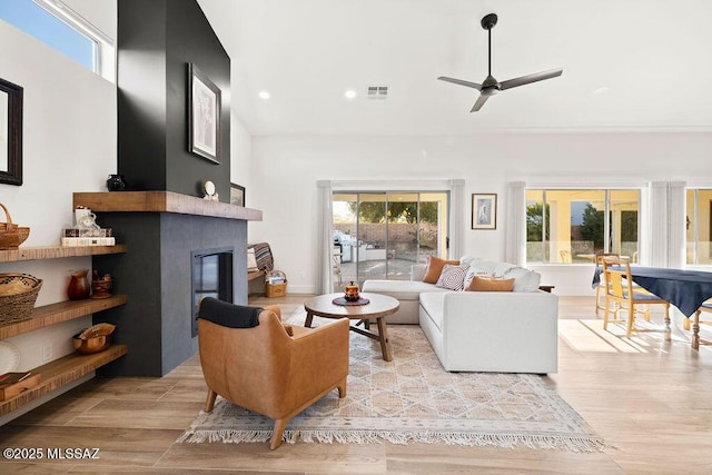 living room featuring a large fireplace and ceiling fan