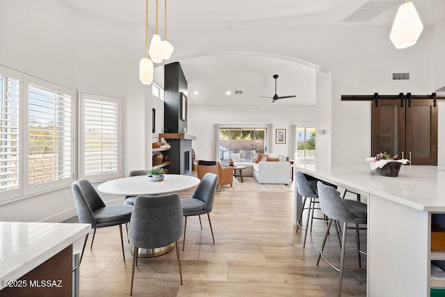 dining area with a barn door and ceiling fan