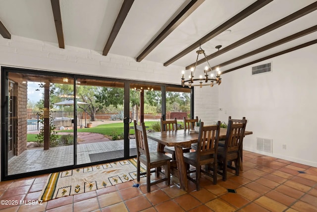 dining area featuring an inviting chandelier, brick wall, beam ceiling, and dark tile patterned flooring