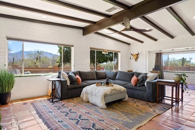 living room with brick wall, lofted ceiling with beams, tile patterned flooring, ceiling fan, and a mountain view