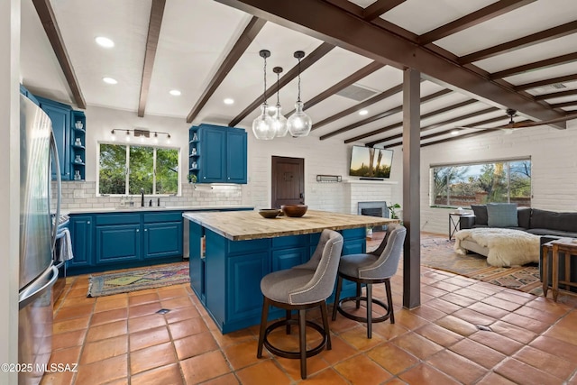 kitchen with pendant lighting, a breakfast bar area, blue cabinetry, and stainless steel refrigerator