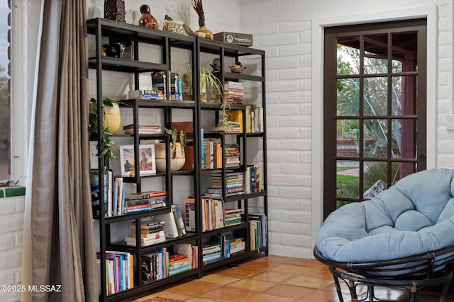 sitting room featuring brick wall and tile patterned flooring