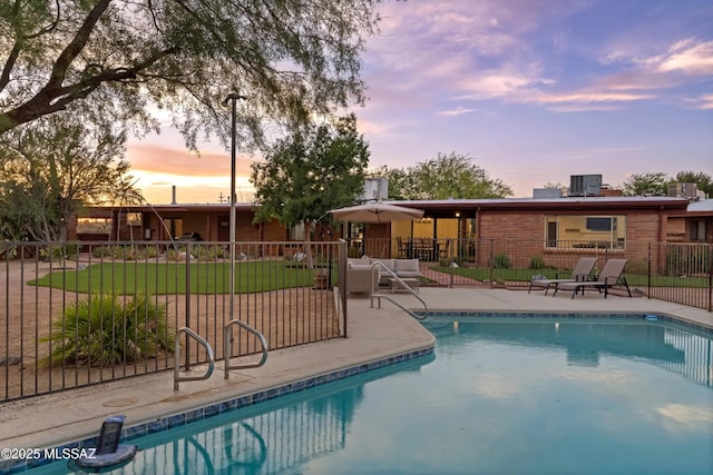 pool at dusk featuring a patio and a yard