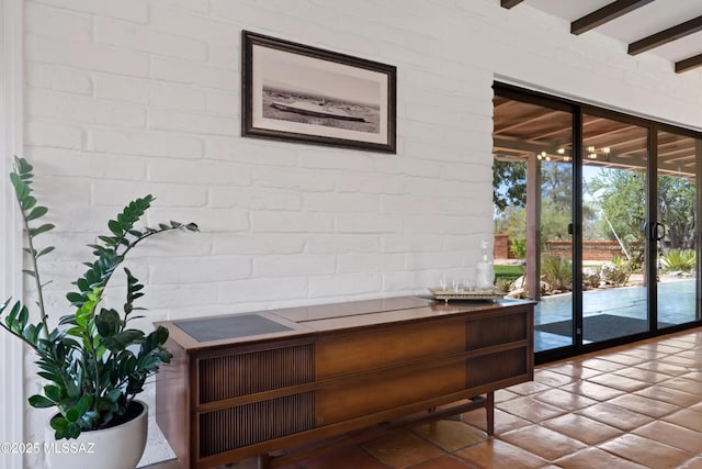 interior space featuring brick wall and beam ceiling