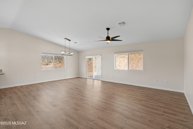 unfurnished living room featuring vaulted ceiling, dark wood-type flooring, a mountain view, and ceiling fan with notable chandelier