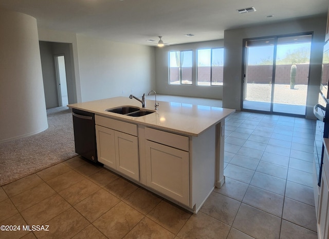 kitchen with black dishwasher, white cabinetry, sink, light colored carpet, and an island with sink