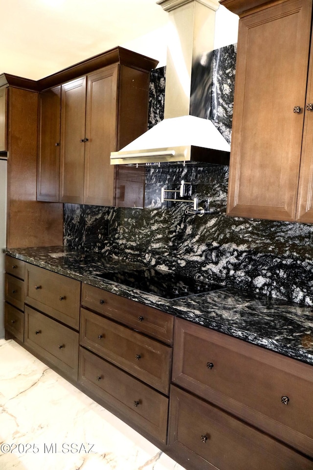 kitchen with backsplash, dark stone counters, black electric stovetop, and wall chimney range hood