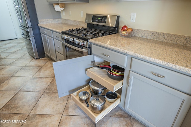 kitchen with light tile patterned floors, light stone countertops, and appliances with stainless steel finishes