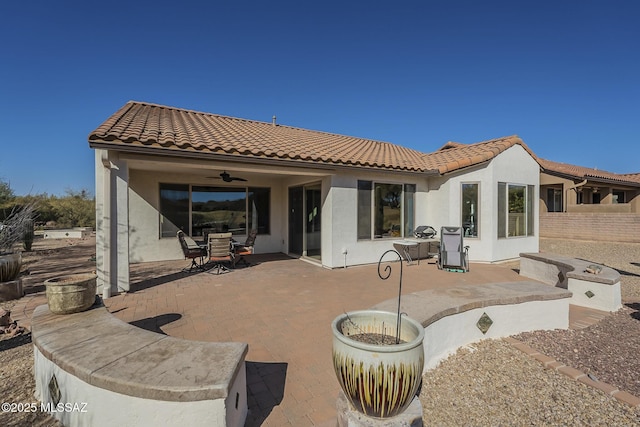 back of property featuring ceiling fan and a patio