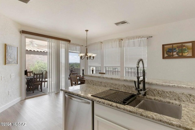 kitchen featuring decorative light fixtures, stainless steel dishwasher, sink, white cabinetry, and light wood-type flooring