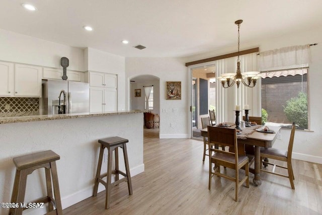 dining room with light hardwood / wood-style floors and a chandelier