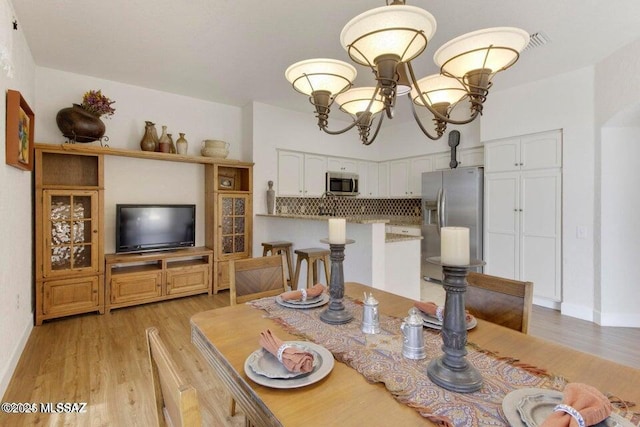 dining area featuring light wood-type flooring and an inviting chandelier