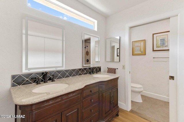 bathroom featuring toilet, vanity, and tasteful backsplash