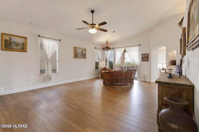 living room featuring vaulted ceiling, ceiling fan with notable chandelier, and dark hardwood / wood-style floors