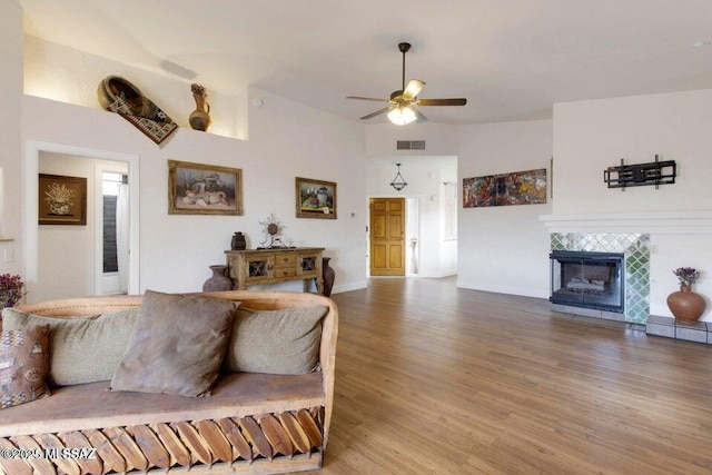 living room featuring ceiling fan, lofted ceiling, a fireplace, and hardwood / wood-style flooring