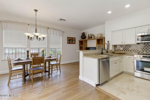 kitchen with sink, white cabinetry, appliances with stainless steel finishes, and hanging light fixtures