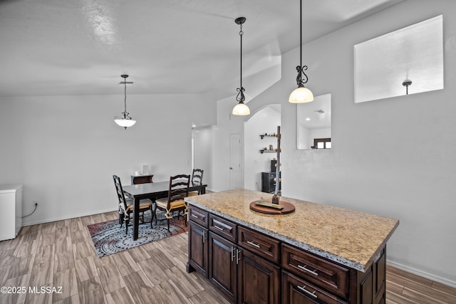 kitchen featuring appliances with stainless steel finishes, hanging light fixtures, sink, a kitchen island, and dark brown cabinetry