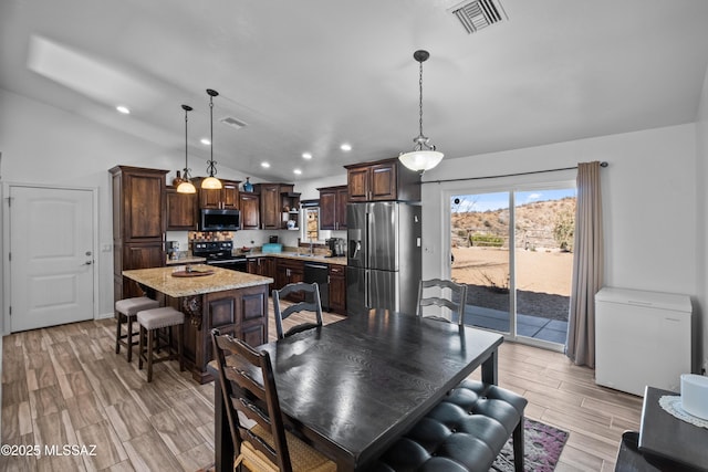 kitchen with pendant lighting, appliances with stainless steel finishes, sink, a kitchen island, and dark brown cabinetry