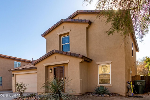 view of front of home featuring stucco siding, an attached garage, and a tiled roof