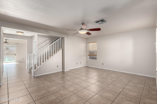 spare room with ceiling fan, a textured ceiling, and light tile patterned floors