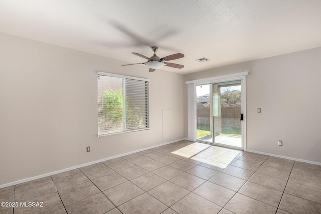 spare room with light tile patterned floors, visible vents, a ceiling fan, and baseboards