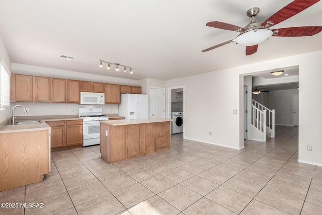 kitchen with sink, white appliances, light tile patterned floors, a kitchen island, and washer / dryer