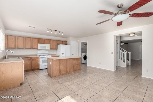 kitchen with white appliances, washer / dryer, a sink, light countertops, and a center island