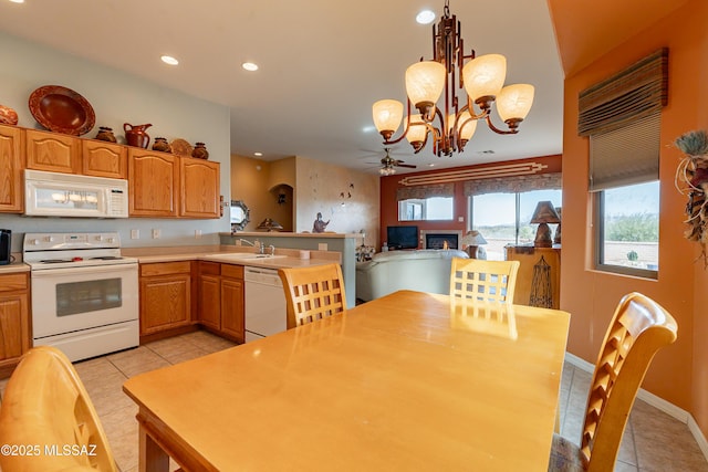 kitchen with sink, hanging light fixtures, light tile patterned floors, kitchen peninsula, and white appliances