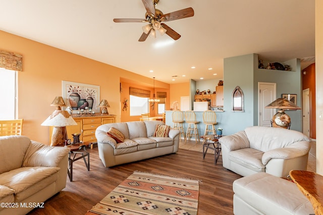 living room with dark wood-type flooring and ceiling fan with notable chandelier