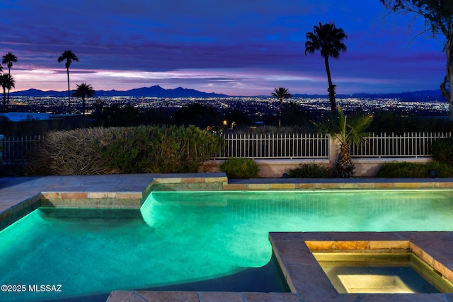 pool at dusk featuring an in ground hot tub